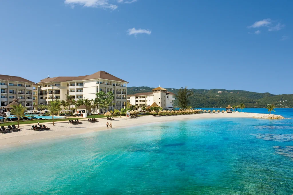 Beachfront view of Secrets Wild Orchid Montego Bay with white sand, turquoise water, and luxury suites.