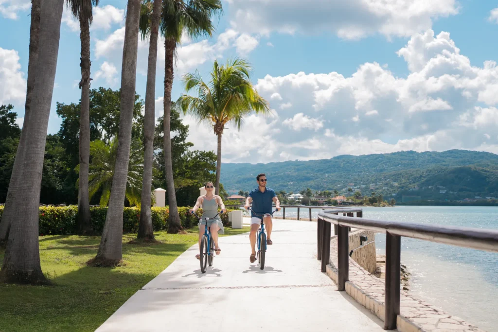 Couple riding bicycles along the oceanfront path at Secrets Wild Orchid Montego Bay in Jamaica.