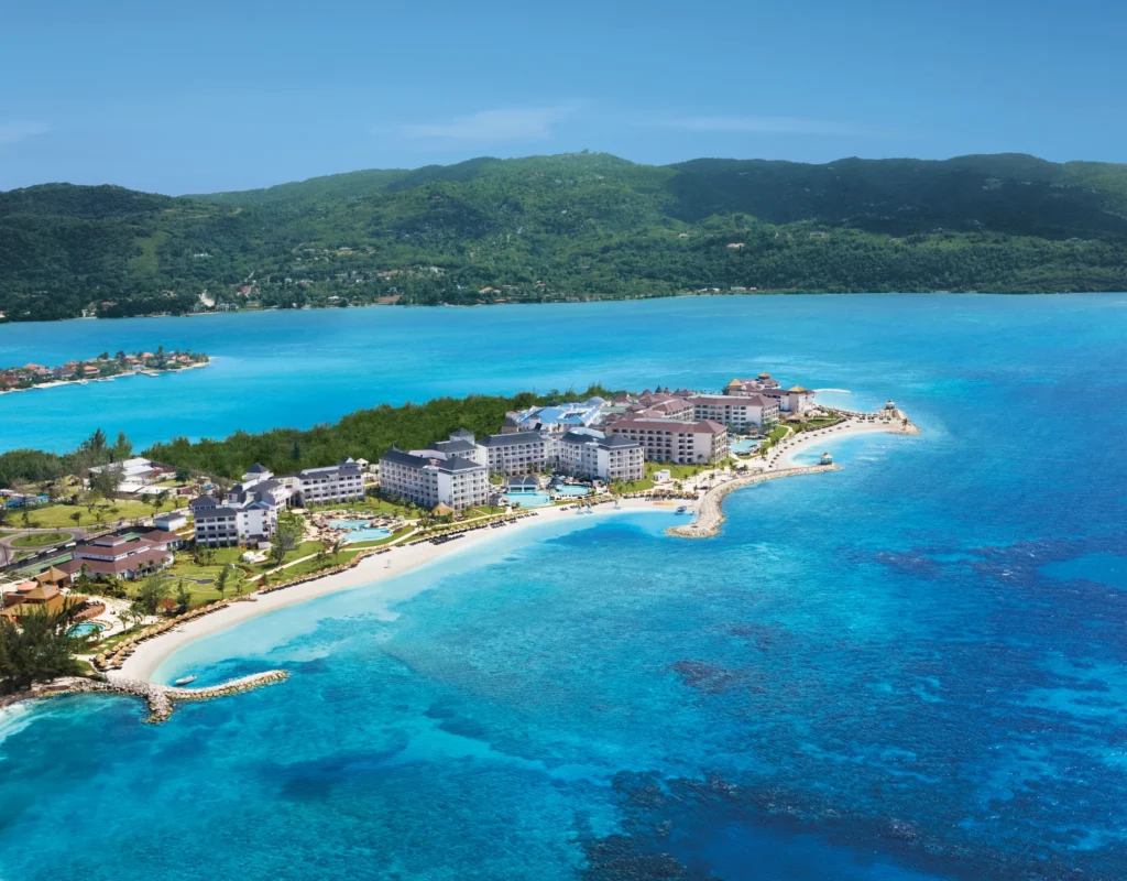 Aerial view of Secrets Wild Orchid Montego Bay overlooking turquoise lagoon waters and surrounding hills in Jamaica.