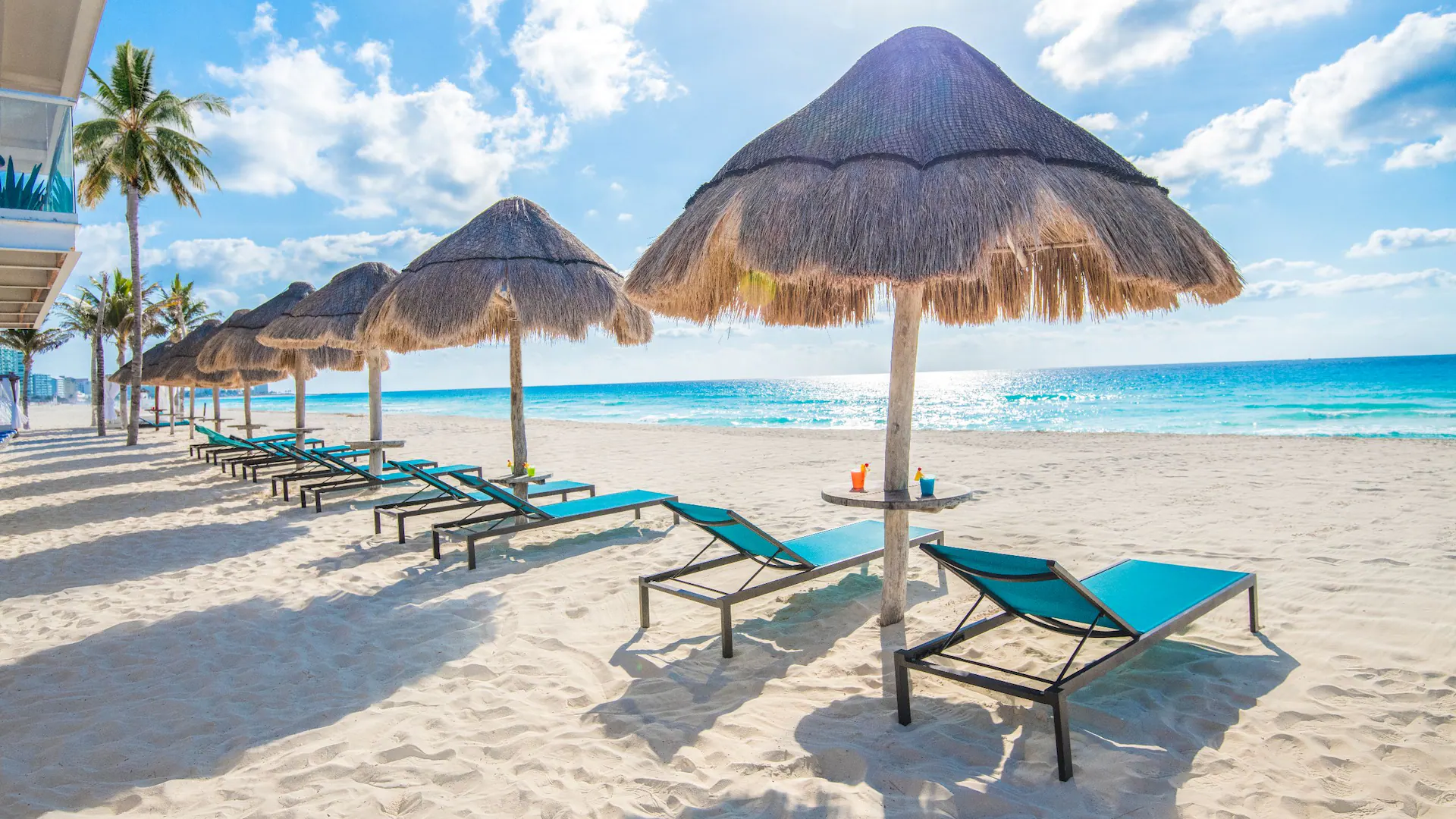 Beach lounge chairs and palapas along the white-sand beach at Sunscape Cancun Resort & Spa.