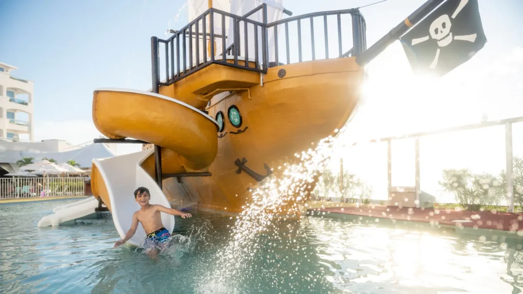 Child enjoying the pirate ship water slide at Sunscape Cancun Resort & Spa family pool area.