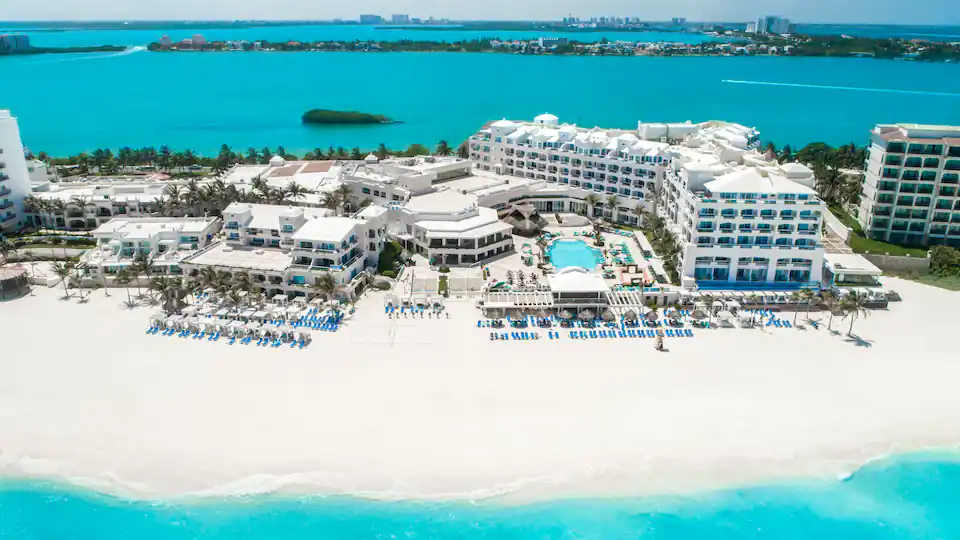 Oceanfront aerial view of Sunscape Cancun Resort & Spa with pools, beach loungers, and turquoise Caribbean waters.