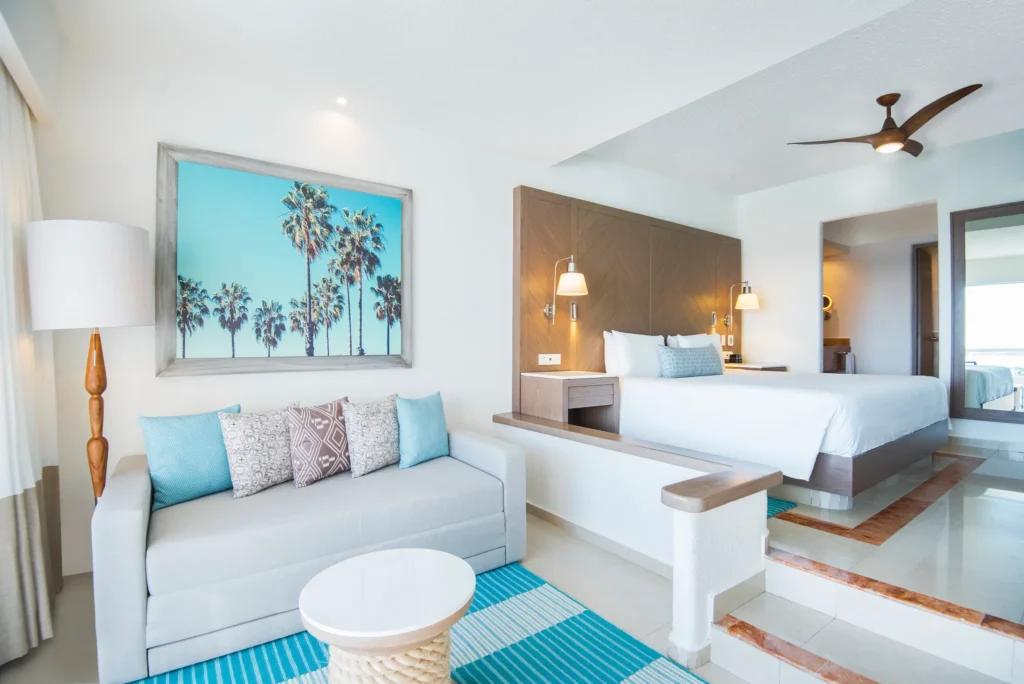 Junior Suite Ocean View living area with sofa and king bed at Sunscape Cancun Resort & Spa.