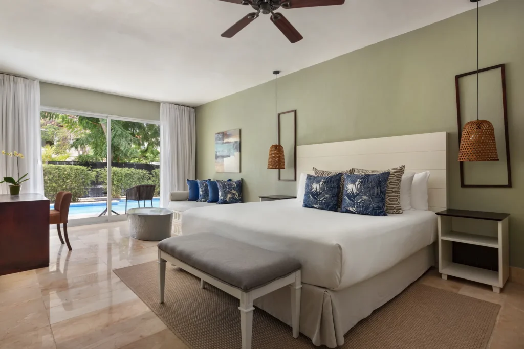 Luxury swim-out junior suite with king bed, tropical décor, and direct pool access at Sunscape Coco Punta Cana.