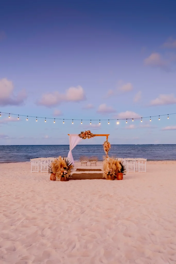 Romantic sunset beach wedding ceremony with string lights at Sunscape Coco Punta Cana Resort.