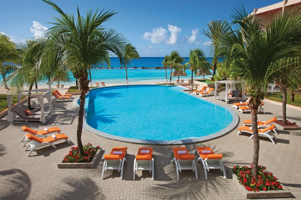 Oceanfront resort pool with palm trees and loungers at Sunscape Curaçao Resort, Spa & Casino.