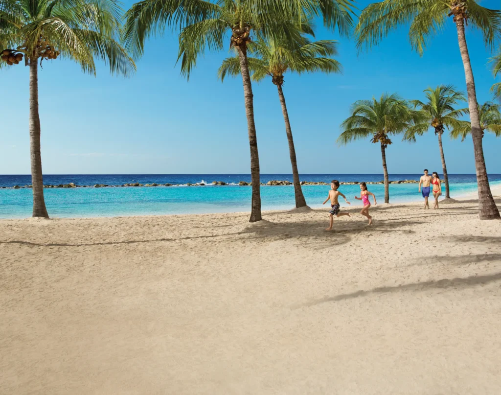 Family walking and children playing on the beach at Sunscape Curaçao Resort, Spa & Casino.