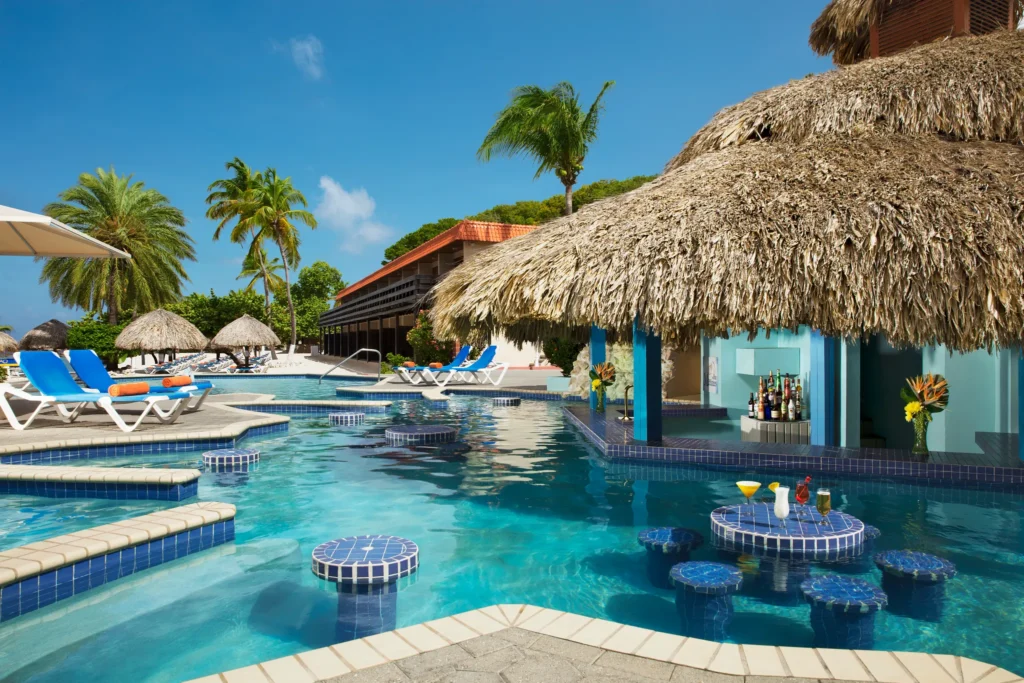 Manatees Swim-Up Bar at Sunscape Curaçao Resort featuring a thatched-roof pool bar with tropical cocktails and in-water seating.