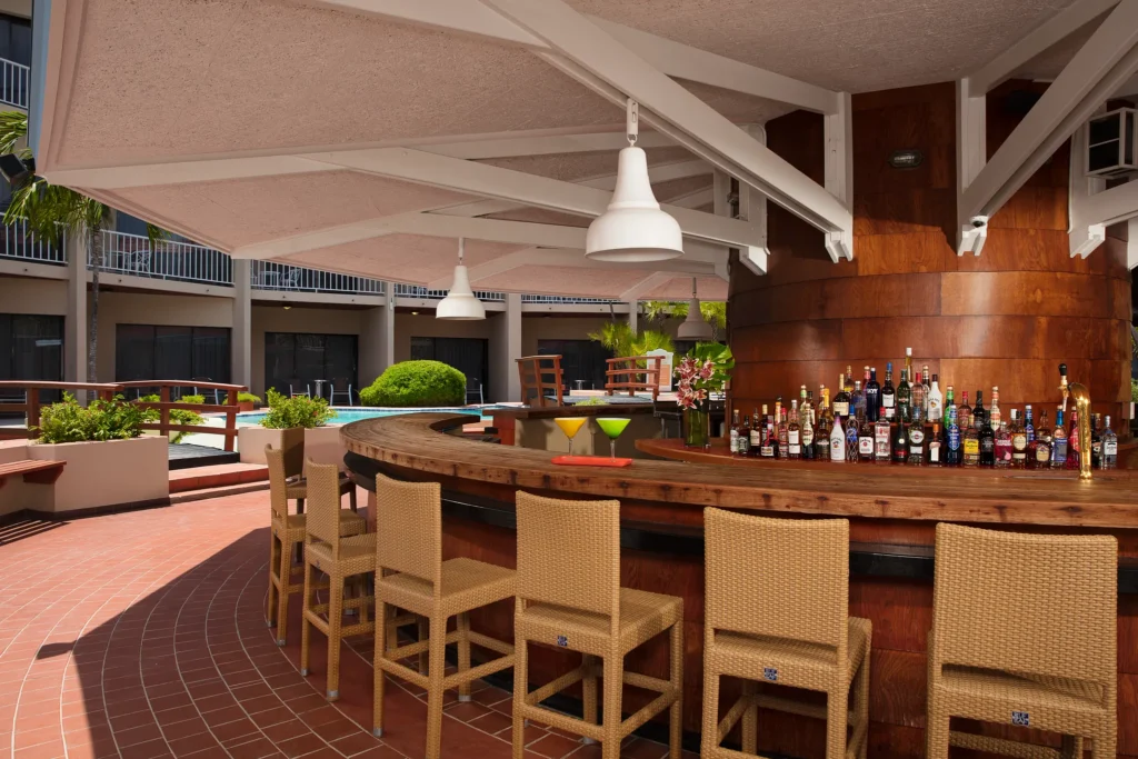 Oceana Bar at Sunscape Curaçao Resort featuring an open-air wooden bar with tropical cocktails near the resort pool and restaurant terrace.