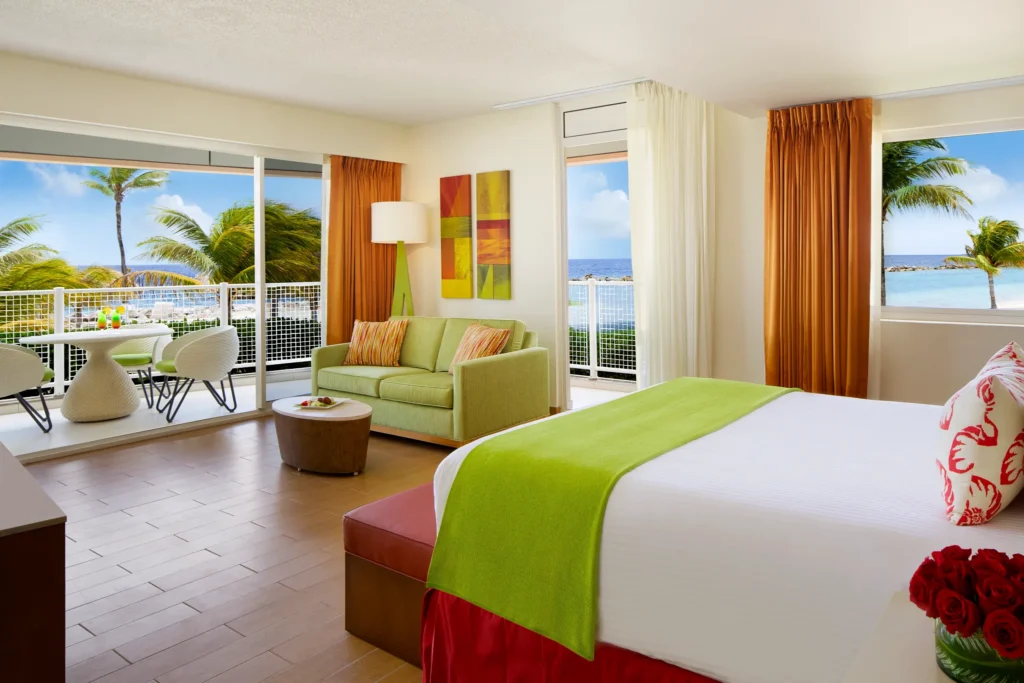 Sun Club Honeymoon Junior Suite Ocean Front with king bed, sofa seating area, and balcony views at Sunscape Curaçao Resort.