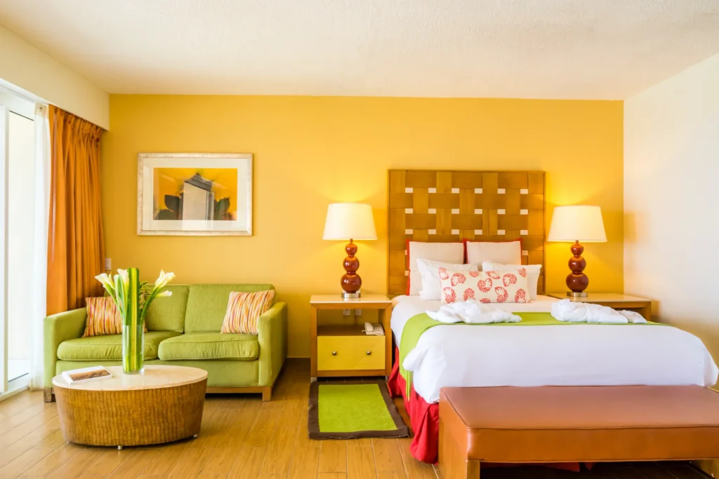 Sun Club Junior Suite Ocean View with double bed, sofa seating area, and bright Caribbean décor at Sunscape Curaçao Resort.