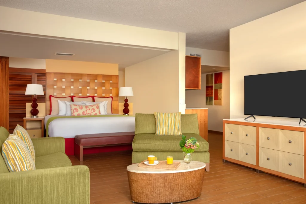 Sun Club Master Suite Ocean Front bedroom with king bed, bedside lamps, and tropical décor at Sunscape Curaçao Resort.
