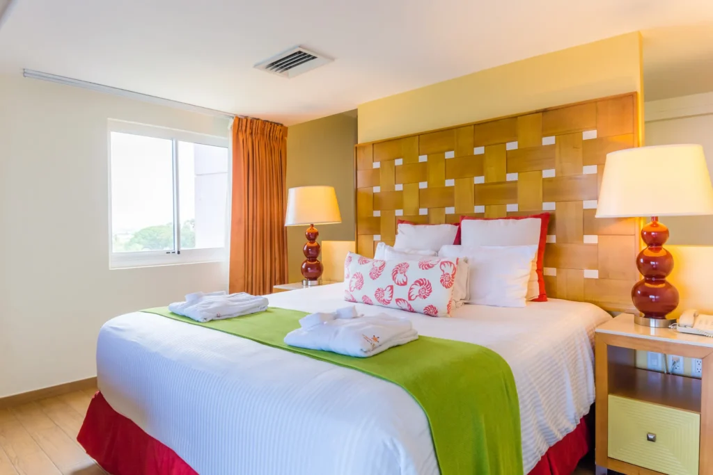 Sun Club Master Suite Ocean Front bedroom and living area with king bed, sofa seating, and TV at Sunscape Curaçao Resort.