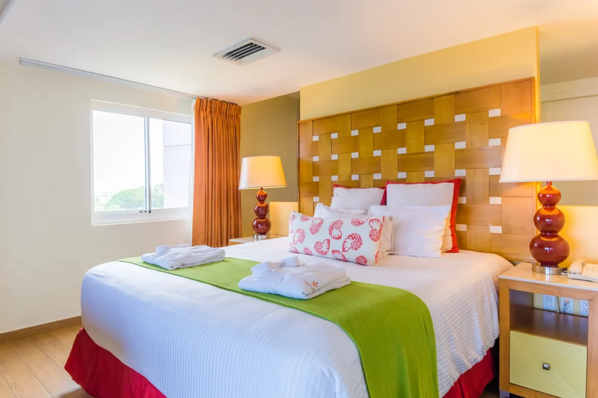 Sun Club Master Suite Ocean Front bedroom and living area with king bed, sofa seating, and TV at Sunscape Curaçao Resort.