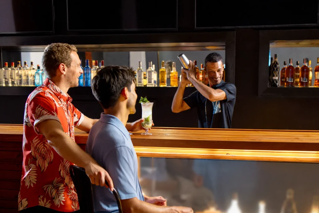 Guests enjoying cocktails at a bar while bartender prepares drinks at Sunscape Dominicus La Romana.