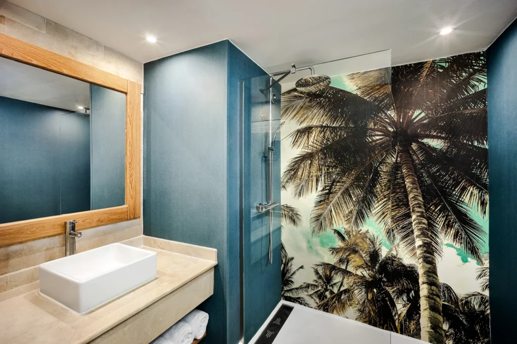 Deluxe Pool View bathroom with walk-in rain shower and tropical palm mural at Sunscape Dominicus La Romana.