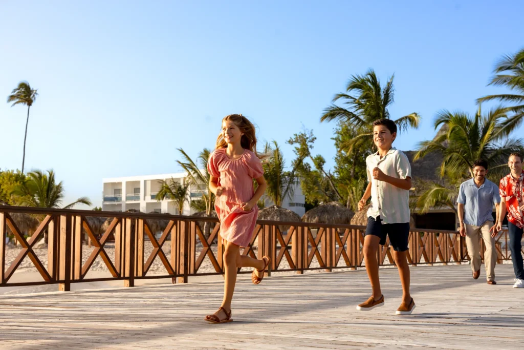 Family enjoying a walk along a wooden boardwalk at Sunscape Dominicus La Romana, perfect for all-ages Caribbean vacations.