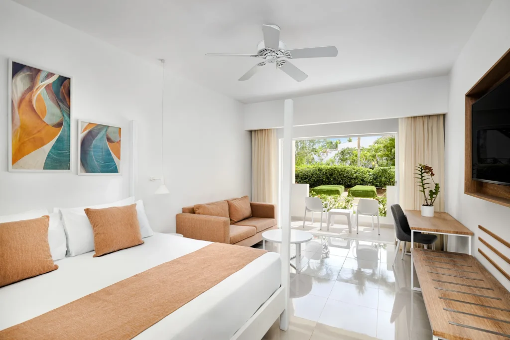 Sun Club Superior Tropical View room with king bed, sofa, and garden view balcony at Sunscape Dominicus La Romana.