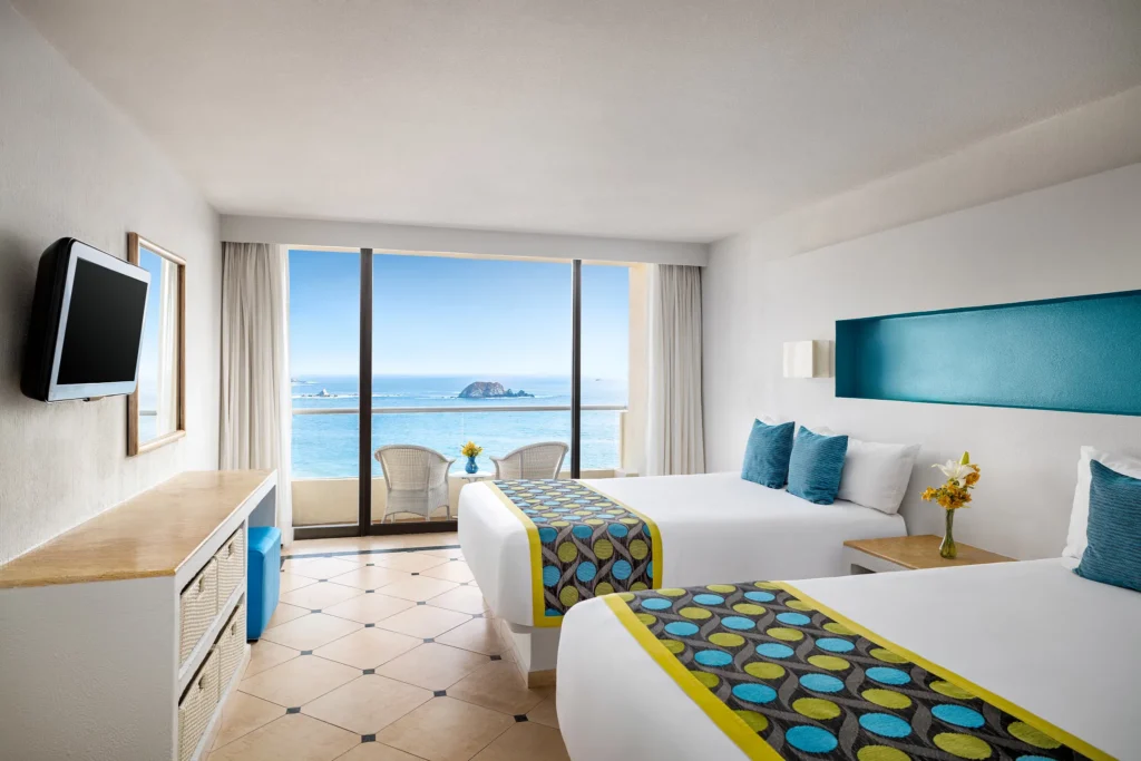 Deluxe Ocean View room with two double beds and private balcony overlooking Palmar Bay at Sunscape Dorado Pacifico Ixtapa.