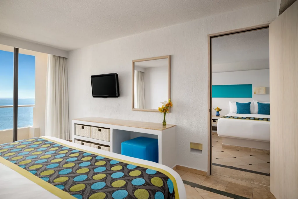 Family Connecting Room with king bed and adjoining double room at Sunscape Dorado Pacifico Ixtapa with partial ocean view balcony.