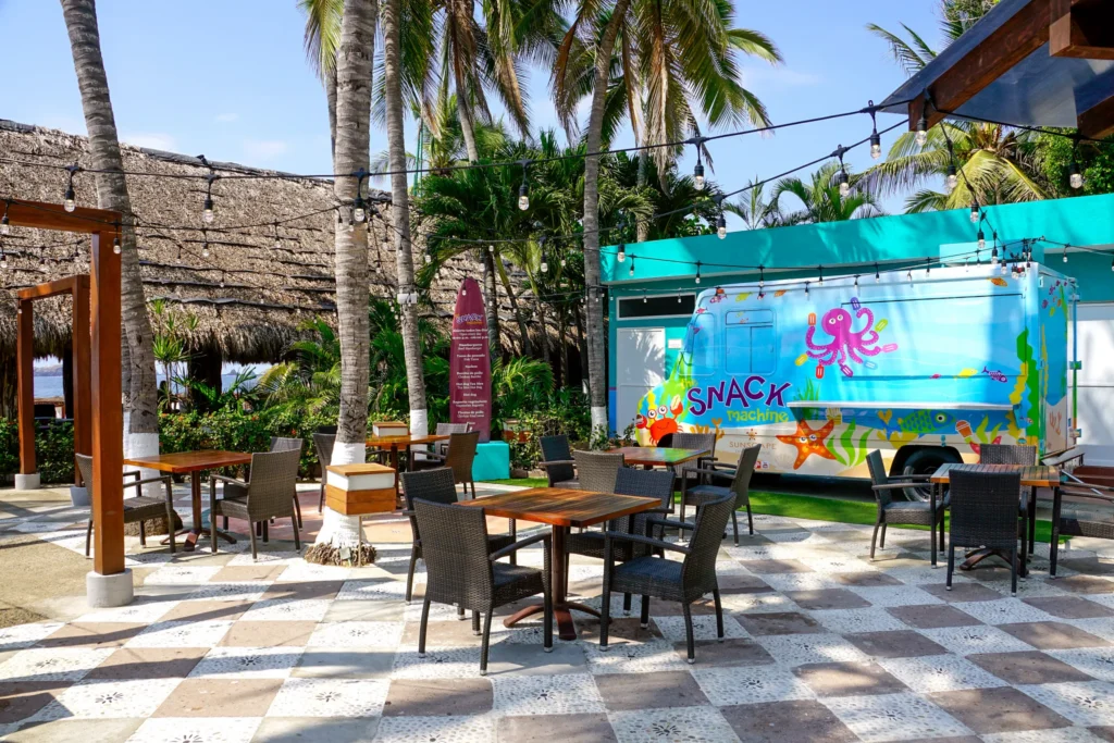 The Snack Machine food truck at Sunscape Dorado Pacifico Ixtapa featuring colorful ocean-themed design, outdoor seating, and tropical palm surroundings.