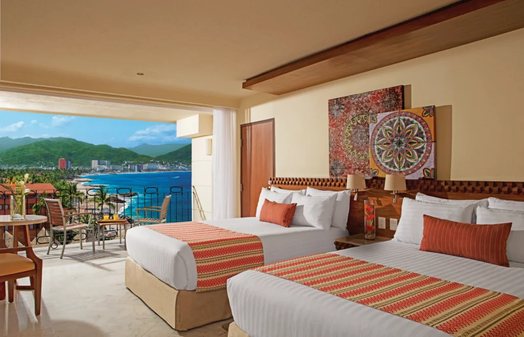 Deluxe Partial Ocean View room with two double beds and private balcony at Sunscape Puerto Vallarta Resort & Spa overlooking the ocean.