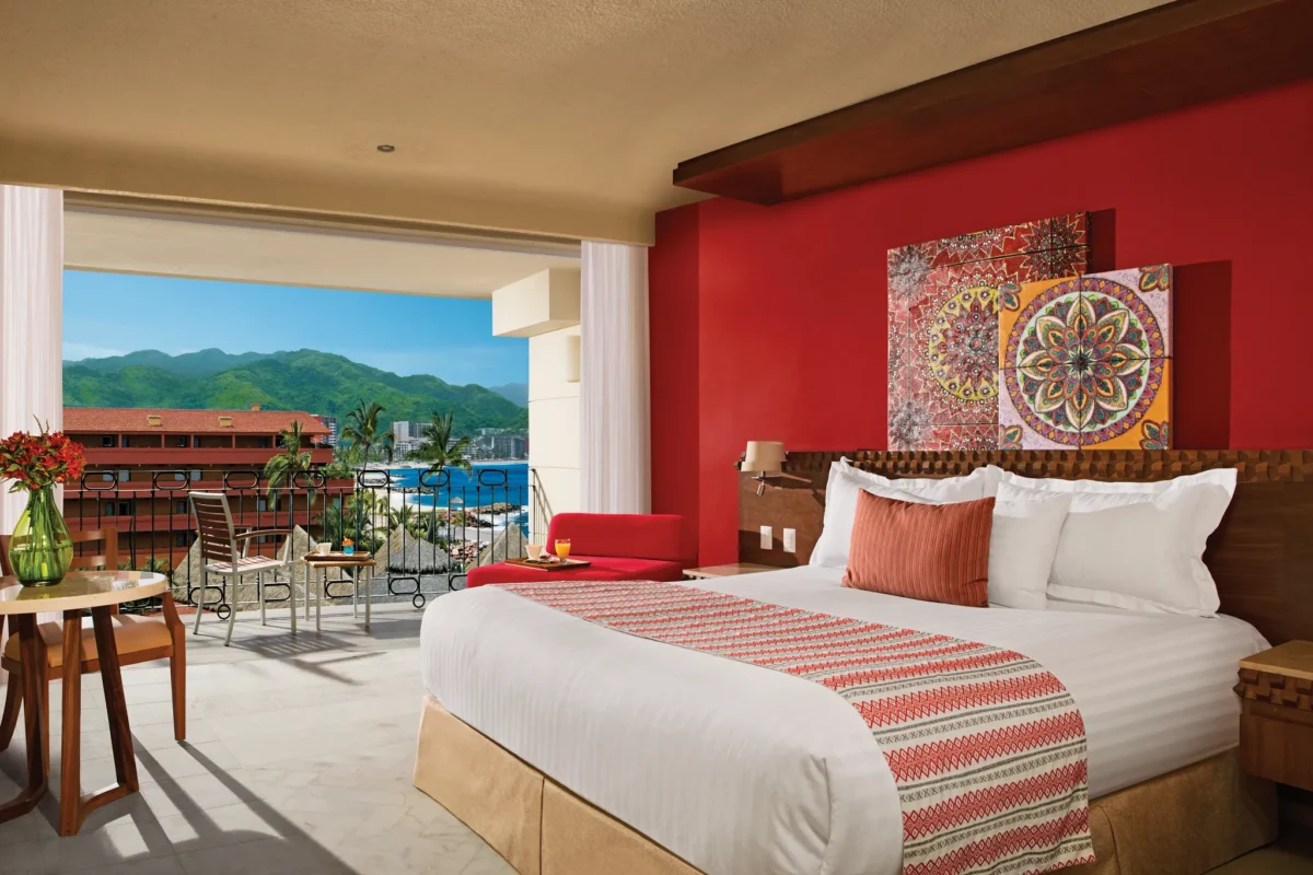 Deluxe Partial Ocean View room with king bed, Huichol-style décor, and private balcony at Sunscape Puerto Vallarta Resort & Spa.