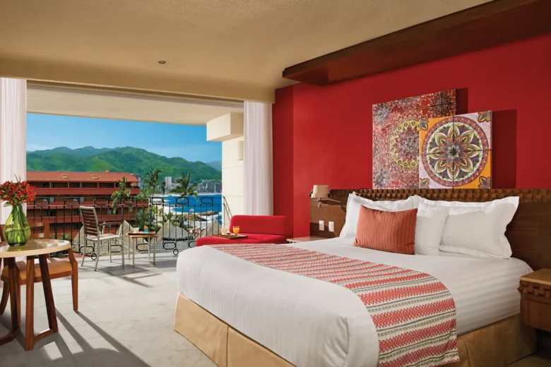 Deluxe Partial Ocean View room with king bed, Huichol-style décor, and private balcony at Sunscape Puerto Vallarta Resort & Spa.