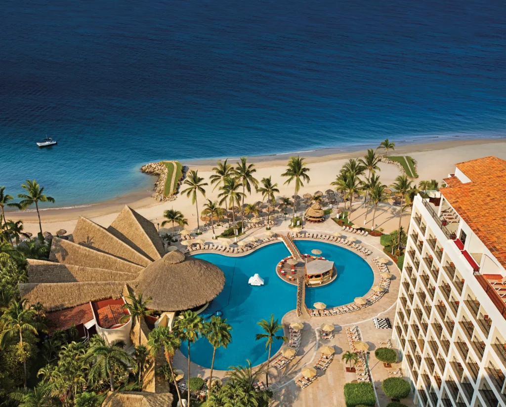 Aerial view of Sunscape Puerto Vallarta Resort & Spa featuring beachfront pools, palm-lined shores, and the Pacific Ocean.