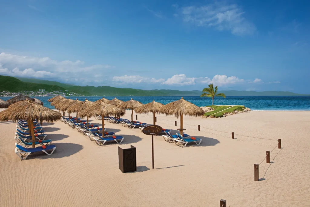 Sun Club beachfront area at Sunscape Puerto Vallarta Resort & Spa with palapa umbrellas, lounge chairs, and ocean views.