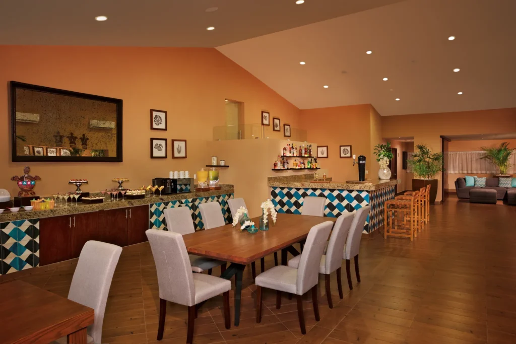 Sun Club Lounge interior at Sunscape Puerto Vallarta Resort & Spa featuring dining tables, a bar area, and comfortable seating for guests.