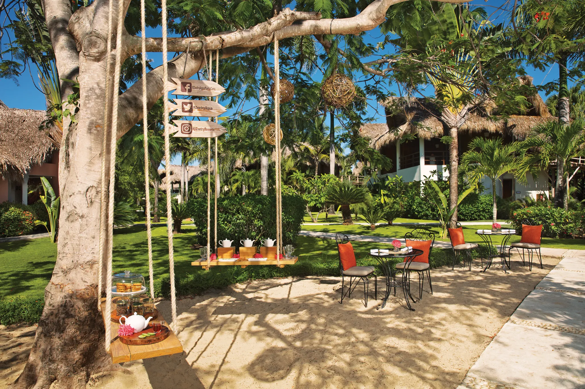Outdoor tea service setup beneath a tree in the tropical gardens of Zoëtry Agua Punta Cana.