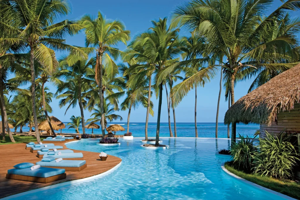 Oceanfront infinity pool with palm trees and lounge beds at Zoëtry Agua Punta Cana.