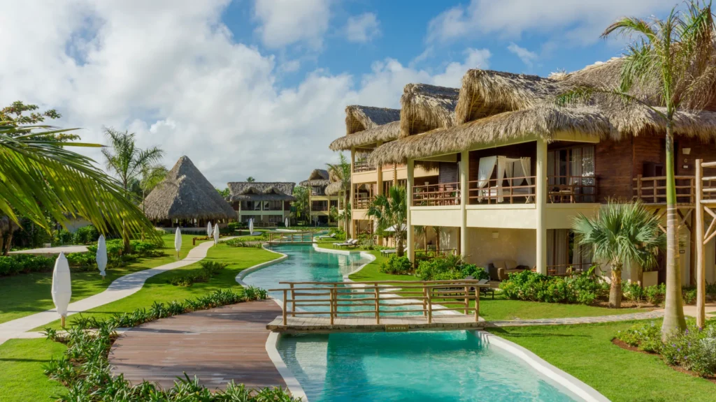 Thatched-roof suites alongside a winding lazy river pool at Zoëtry Agua Punta Cana beachfront resort.