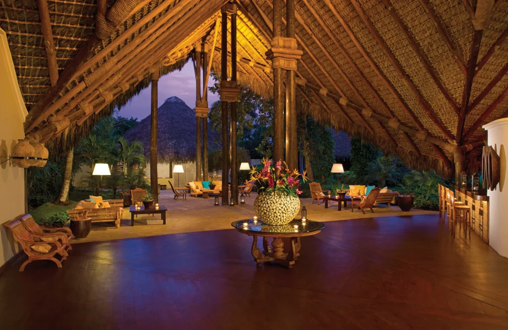 Open-air thatched-roof lobby lounge at Zoëtry Agua Punta Cana at sunset.