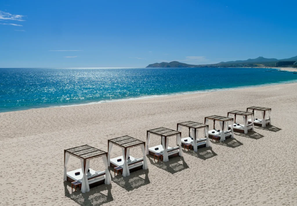 Private beach daybeds lined along sandy shore at Zoëtry Casa del Mar Los Cabos with ocean views.