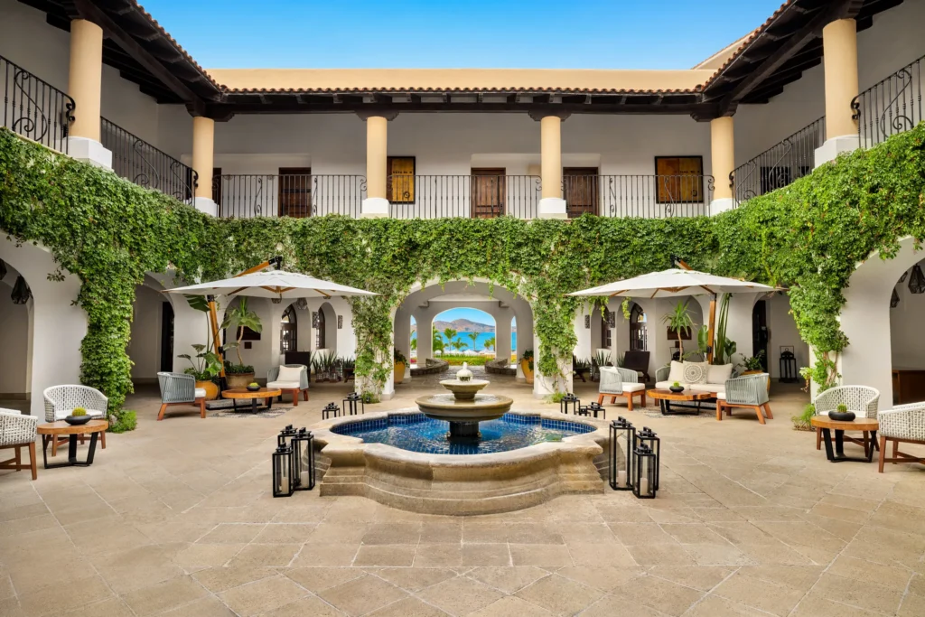 Elegant courtyard lobby with fountain and ocean view at Zoëtry Casa del Mar Los Cabos, featuring lush greenery and hacienda-style architecture.