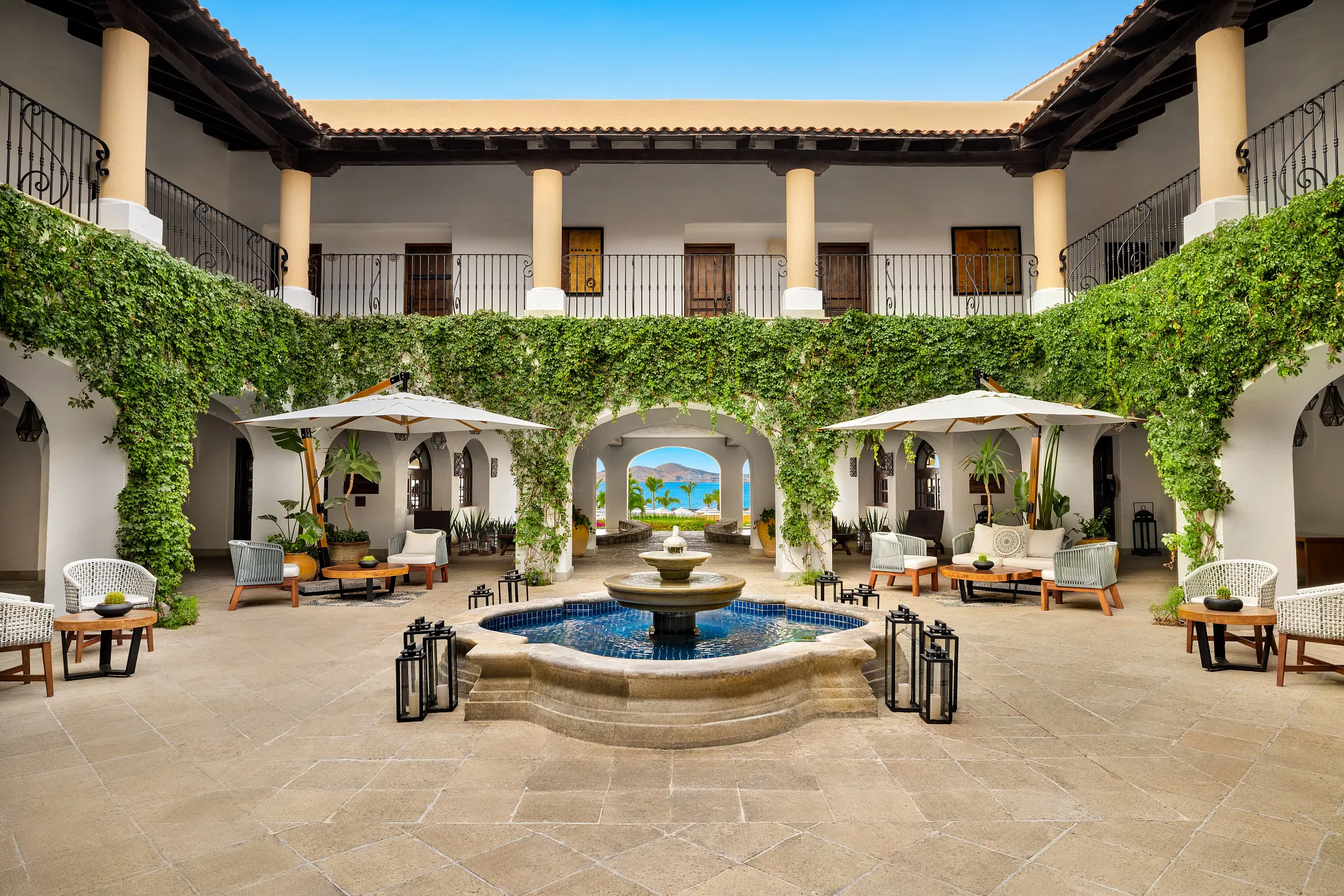 Elegant courtyard lobby with fountain and ocean view at Zoëtry Casa del Mar Los Cabos, featuring lush greenery and hacienda-style architecture.