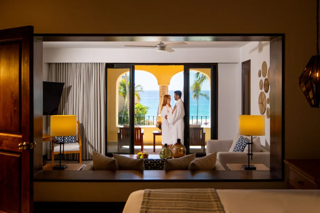 Oceanfront suite interior view with couple on balcony at Zoëtry Casa del Mar Los Cabos.