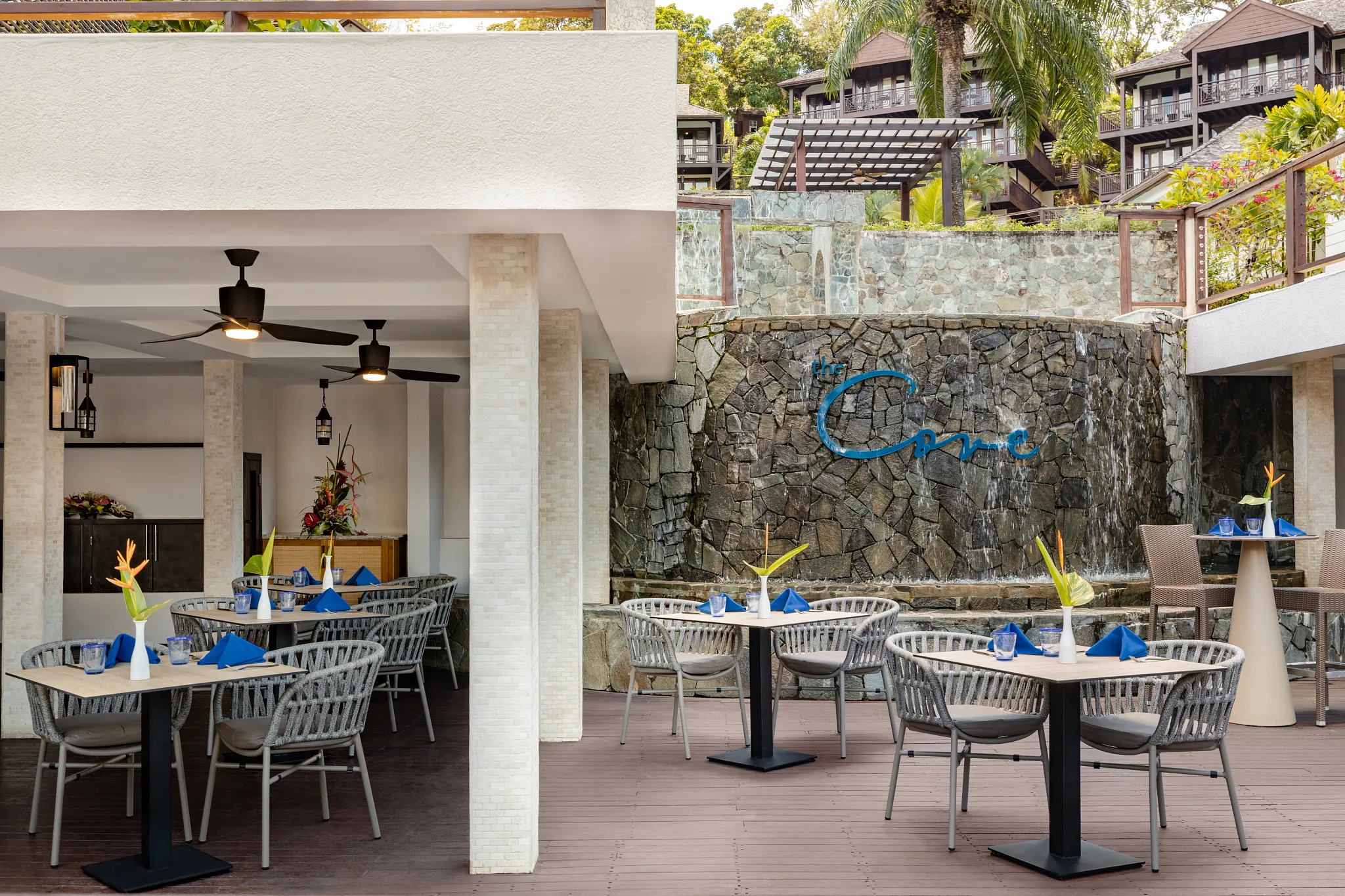 The Cove restaurant at Zoëtry Marigot Bay St. Lucia featuring outdoor terrace dining beside a waterfall and lush tropical hillside views.