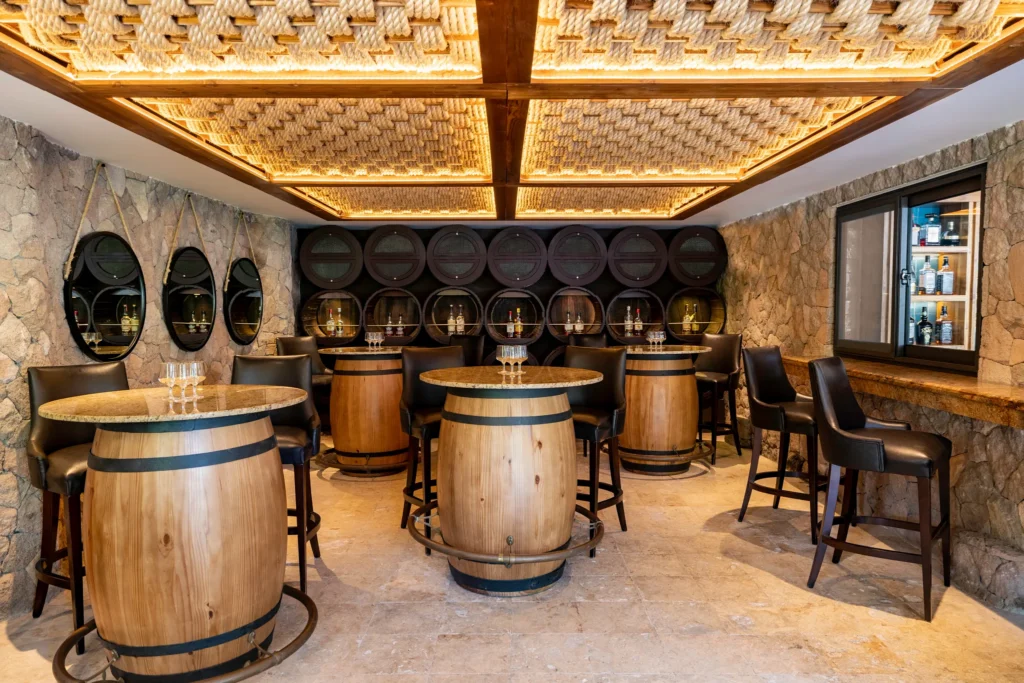 The Rum Cave at Zoëtry Marigot Bay St. Lucia featuring an intimate lounge with barrel tables, stone walls, and specialty rum displays.