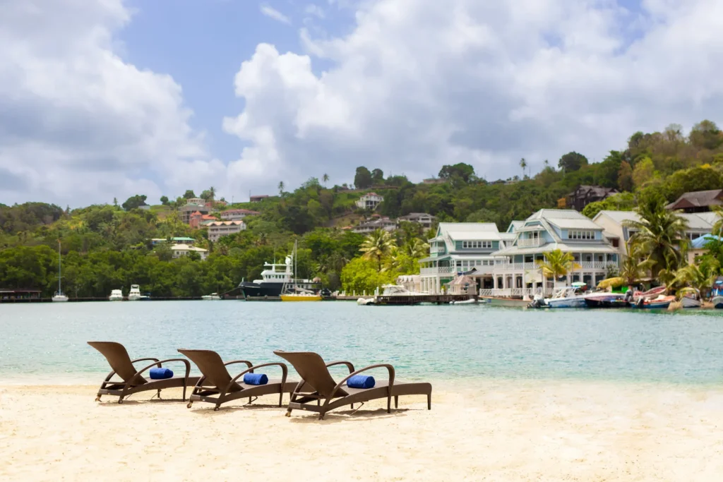 Lounge chairs set on a sandy beach near Zoëtry Marigot Bay St. Lucia overlooking calm Caribbean waters.