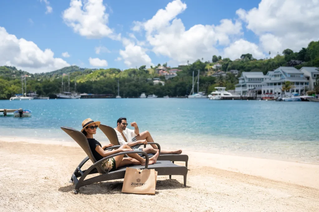Couple relaxing on beach loungers at Zoëtry Marigot Bay St. Lucia overlooking crystal-clear Caribbean waters.