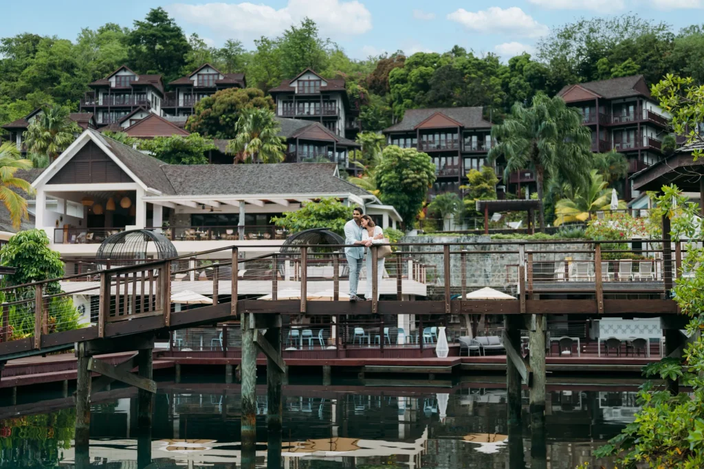 Romantic couple standing on a wooden bridge overlooking the marina at Zoëtry Marigot Bay St. Lucia.