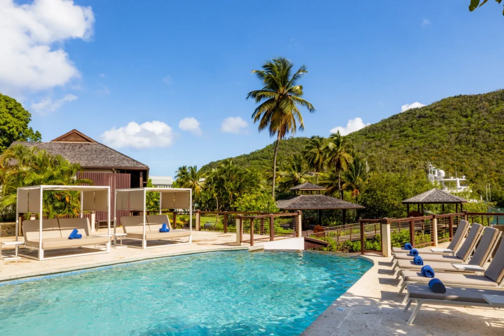 Infinity-style pool with sun loungers and palm trees at Zoëtry Marigot Bay St. Lucia overlooking tropical hills.