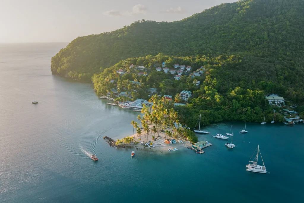 Aerial view of LaBas Beach near Zoëtry Marigot Bay St. Lucia with palm trees and anchored boats.