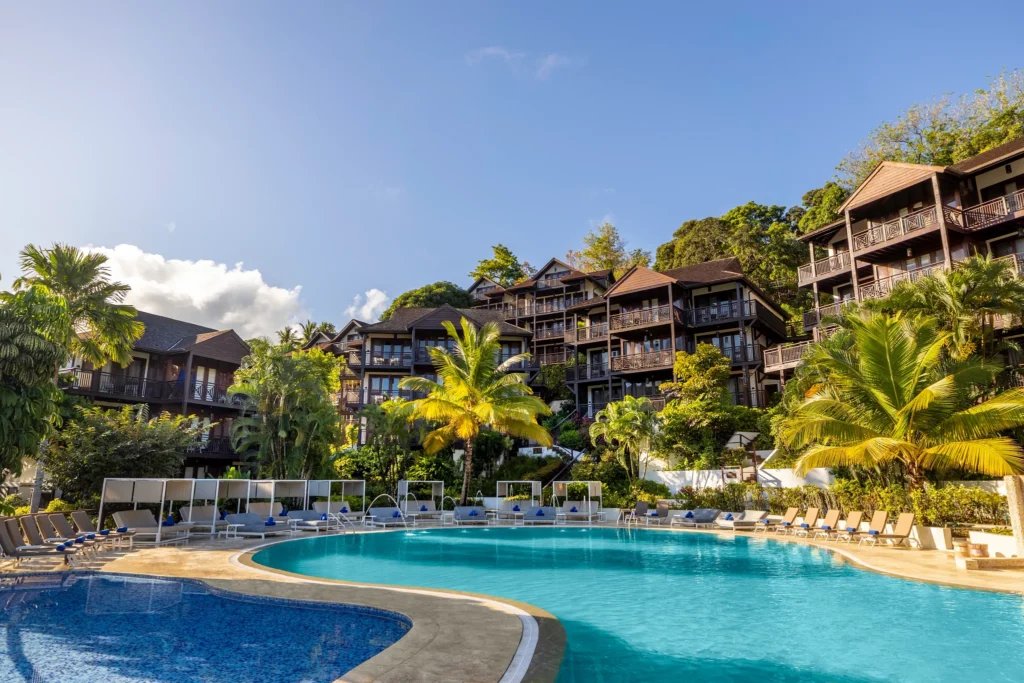 Lagoon-style main pool at Zoëtry Marigot Bay St. Lucia with hillside suites and palm trees in the background.