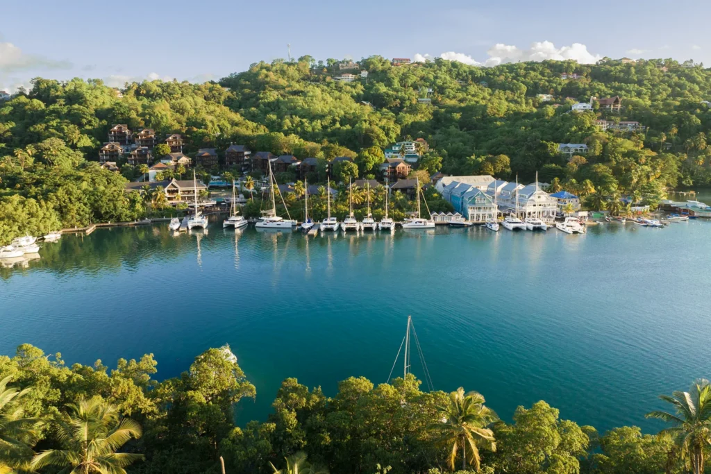 Panoramic marina view at Zoëtry Marigot Bay St. Lucia with sailboats docked along the waterfront and lush hillside backdrop.