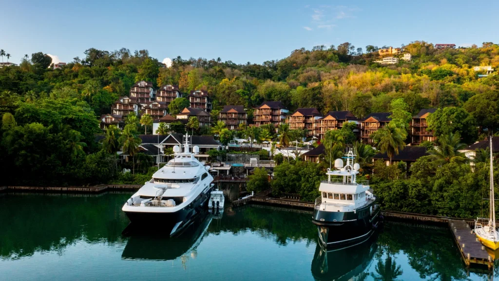 Luxury yachts docked at the marina in front of Zoëtry Marigot Bay St. Lucia surrounded by lush hills.