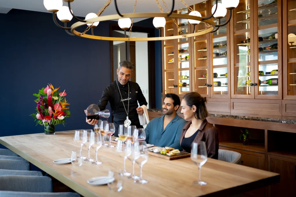 Sommelier pouring red wine for a couple during a wine tasting experience at Zoëtry Marigot Bay St. Lucia.